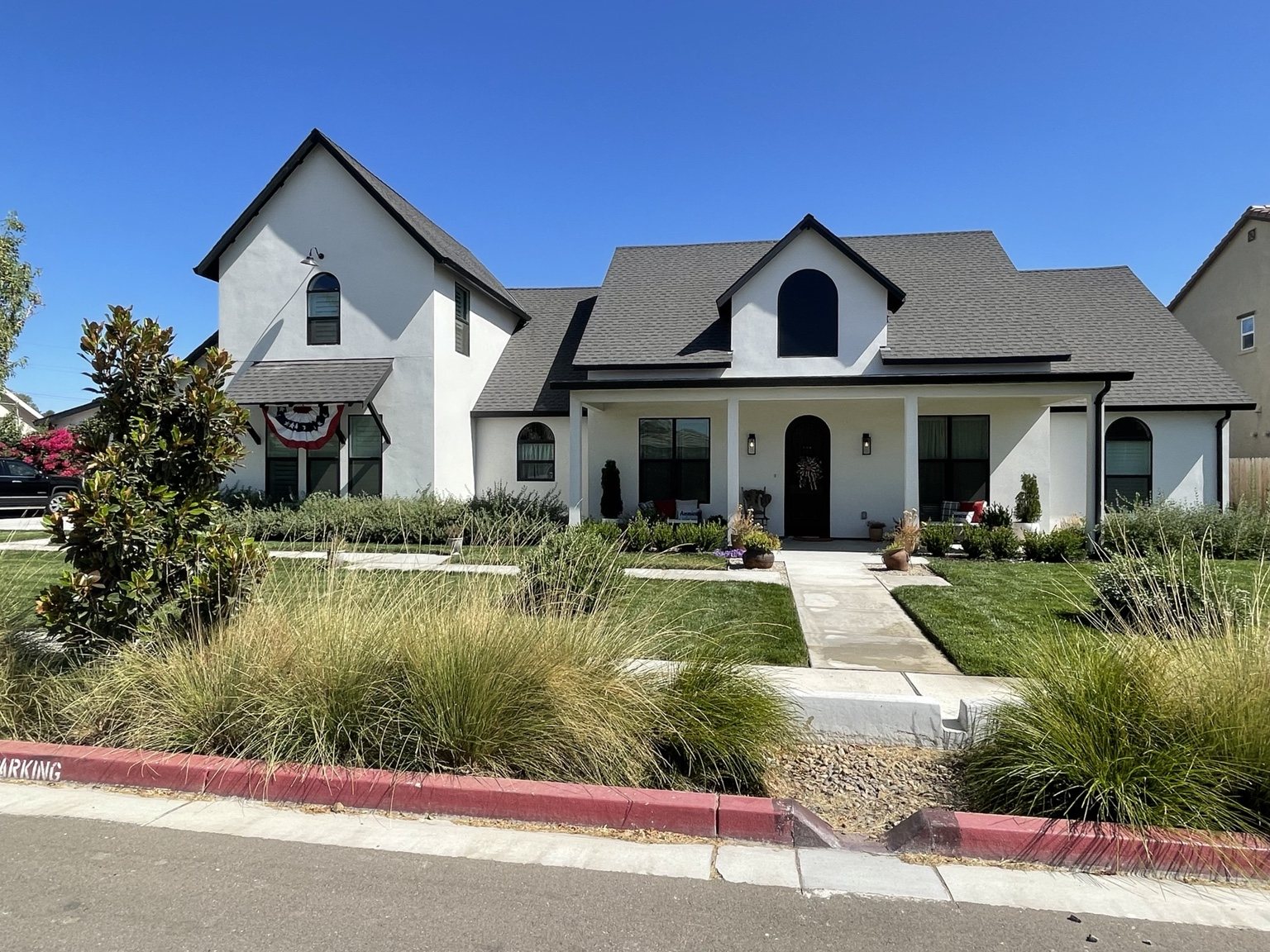 White custom residence with gabled rooflines and arched windows