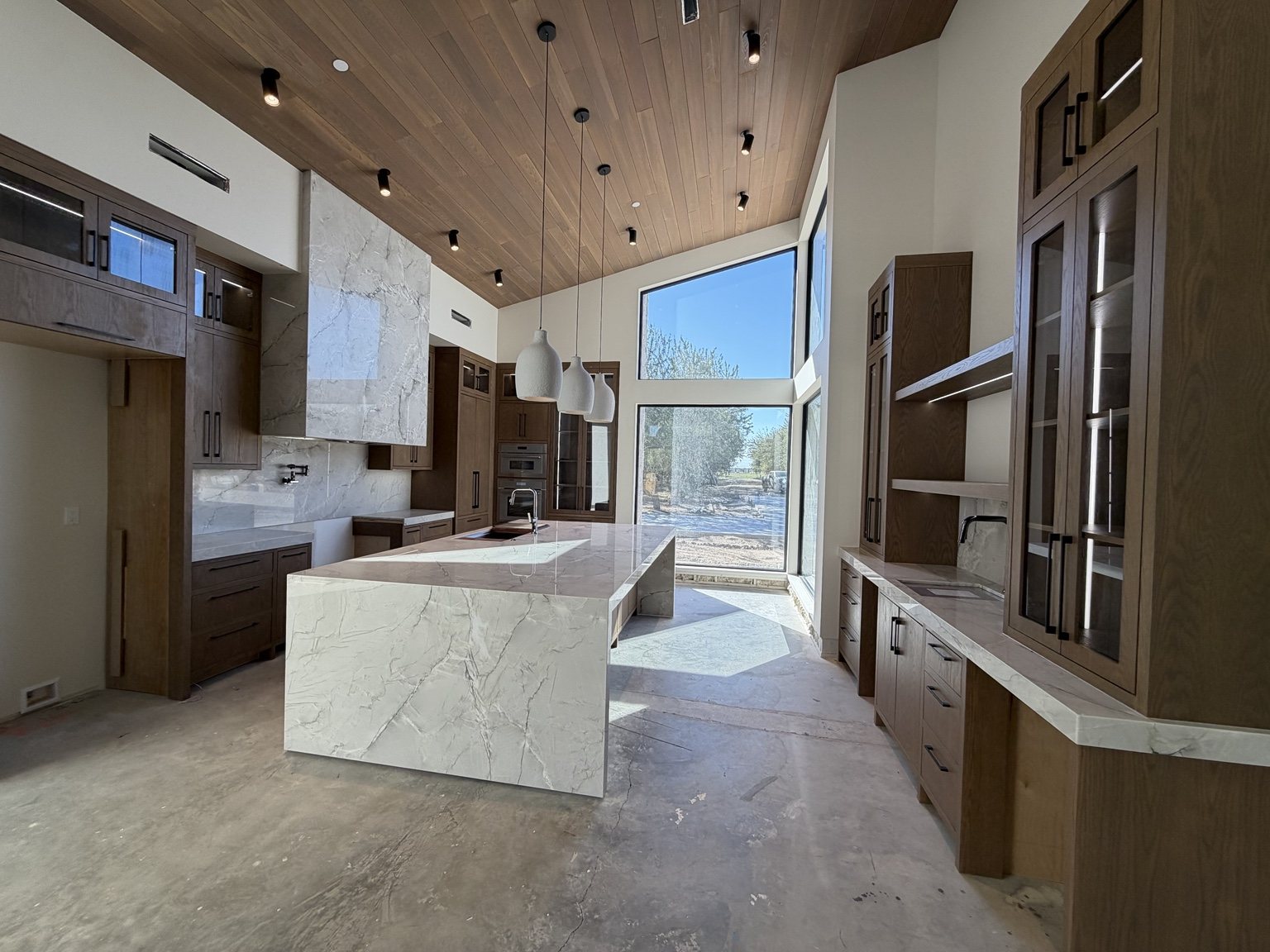 Custom kitchen with stone waterfall island and wood ceiling
