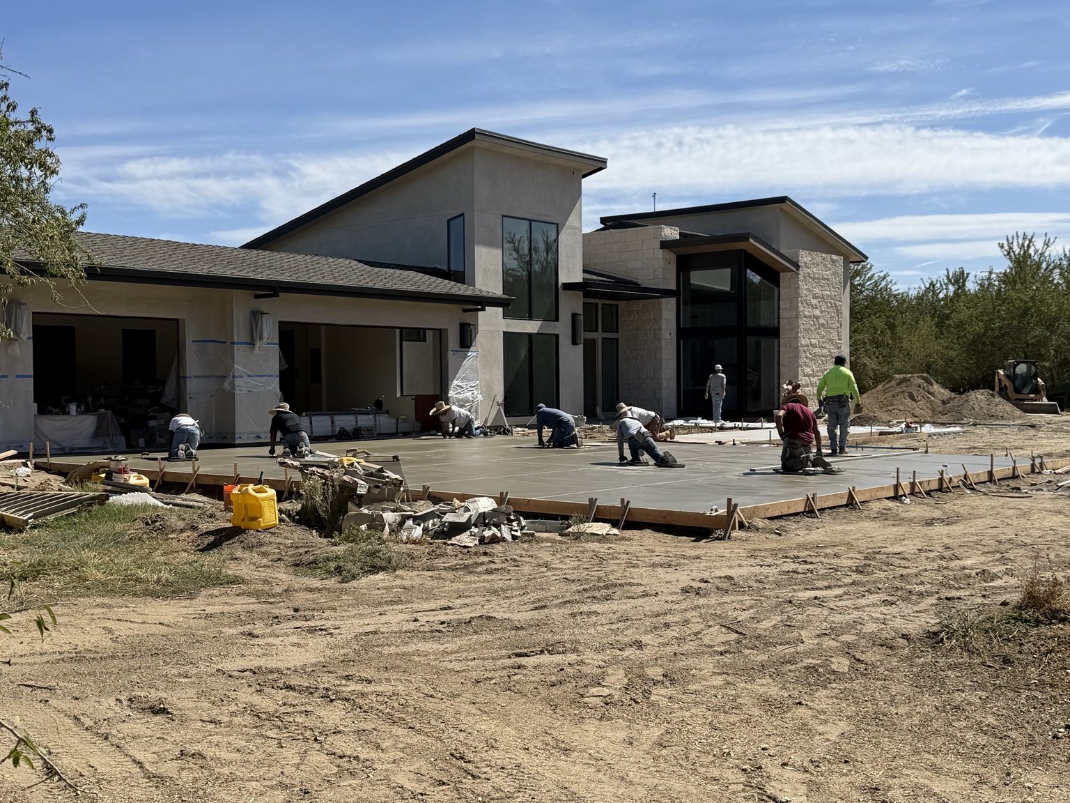 Crew finishing concrete outside a custom home